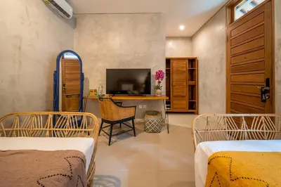 a room with two beds and a desk with a television at Little Boutique Hotel 106- 30m from beach in Canggu