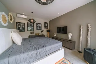 a bedroom with a large bed and a flat screen tv at Villa Batik - Brand New & Stylish 3BR Villa in Seminyak! in Seminyak