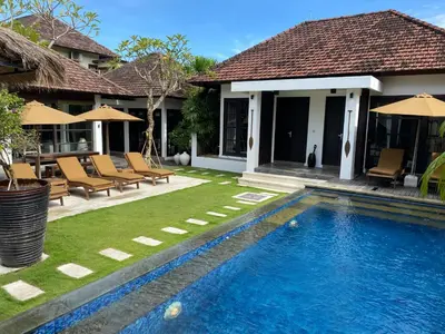 a swimming pool in front of a house at Lotus Luxury Villa Seminyak in Seminyak