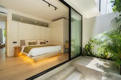 a bedroom with a bed and a glass wall at Oasis Villa 8 by Betterplace in Canggu