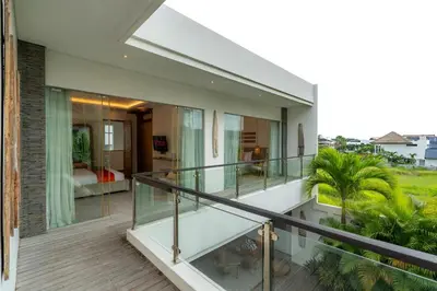 a balcony of a house with glass railing at Flores Villa by Betterplace in Canggu