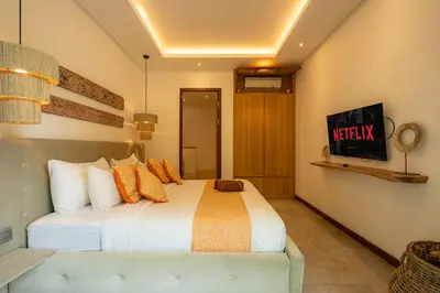 a bedroom with a large white bed with orange pillows at Flores Villa by Betterplace in Canggu
