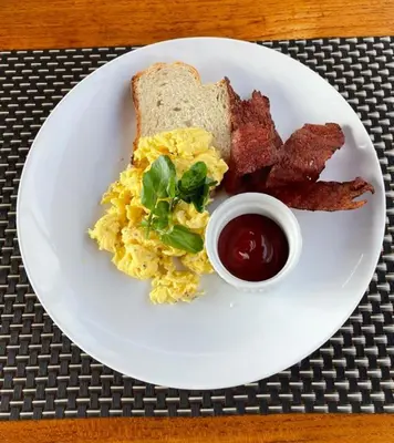 a white plate with eggs bacon bacon and toast at Kos Bulan Bali in Kuta