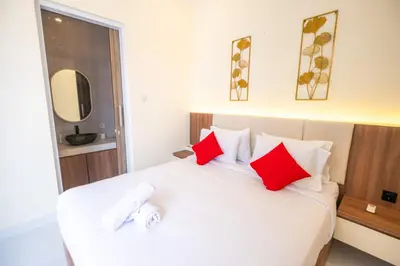 a bedroom with a large white bed with red pillows at Villa Kamandari in Kuta