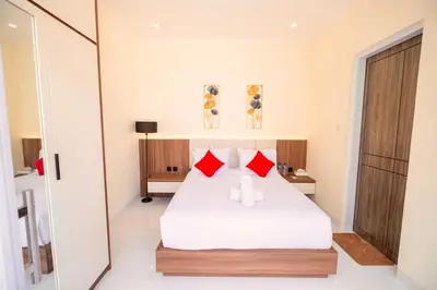 a bedroom with a white bed with red pillows at Villa Kamandari in Kuta