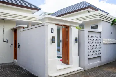 a white house with a wooden door at Villa Kamandari in Kuta