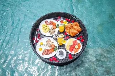 a tray of food on a table in the water at Zayana Villas Resort Seminyak in Seminyak