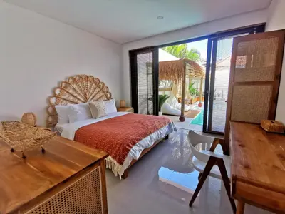 a bedroom with a bed and a view of a pool at Villa Anoli - 3 chambres - Centre de Seminyak in Seminyak
