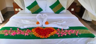 a bed with two towels and flowers on it at Jimbaran BeachStroll Villa (2BR) in Jimbaran