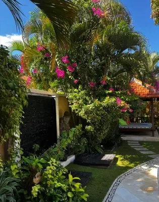 a garden with pink flowers and a palm tree at Villa Mango - 3 Bedroom Villa in Seminyak in Seminyak