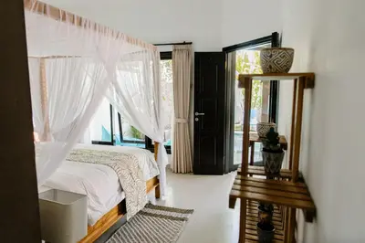 a bedroom with a bed and a mirror and a window at Saga Villas Oasis in Seminyak