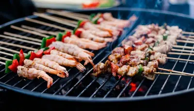 a bunch of skewers cooking on a grill at Cempaka Villa by Premier Hospitality Asia in Nusa Dua