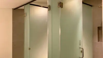 a glass shower door in a bathroom at White Penny Hostel in Seminyak