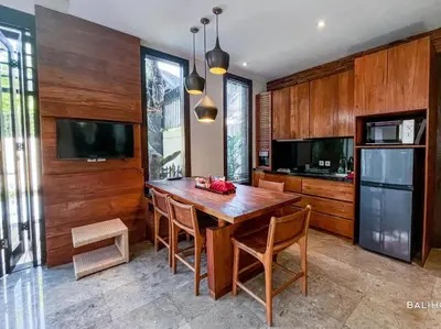 a kitchen with a wooden table with chairs and a television at Villa Canthy@Seminyak in Seminyak