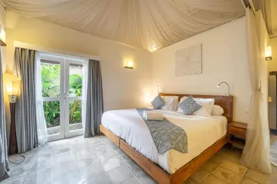 a bedroom with a bed and a large window at Nameera Villa in Seminyak