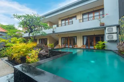a swimming pool in front of a house at Liliy Guest House Kuta in Legian