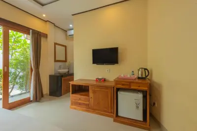 a room with a tv on the wall at Liliy Guest House Kuta in Legian