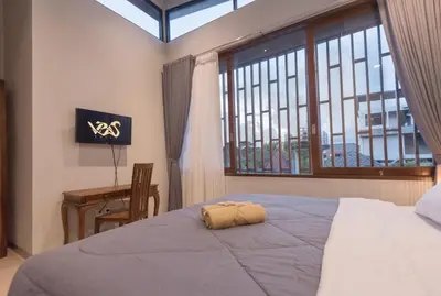 a bedroom with a bed and a desk and a window at Vpas Villa in Seminyak