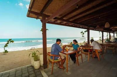 a group of people sitting at tables on the beach at Tropical Beach House Bali in Seminyak