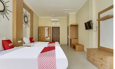a hotel room with two beds and a tv at Moreno Homestay in Legian