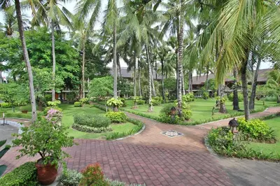 a garden with palm trees and a brick walkway at Club Bali Suite Legian in Legian