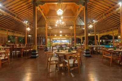 a restaurant with tables and chairs and a pool at Villa Burung in Kashantee Village in Seminyak