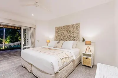 a white bedroom with a bed and a window at Baliani Beauty in Seminyak