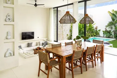 a dining room with a wooden table and chairs at Casa Umalas Villa by Betterplace in Canggu