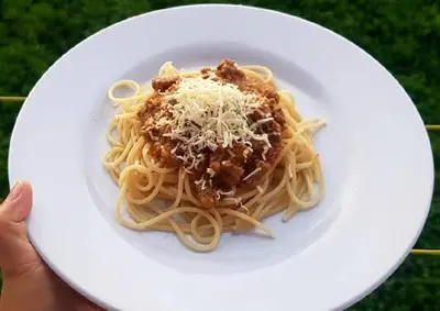 a person holding a plate of pasta with cheese at 9 Residence's Seminyak in Seminyak