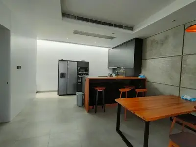 a kitchen with a wooden table and a refrigerator at Milo Modern Five-Bedrooms Villa in Jimbaran