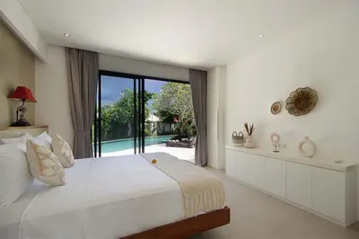 a white bedroom with a large bed and a large window at Villa Papaya by Optimum Bali Villas in Canggu