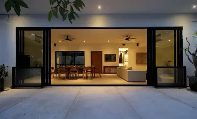 a living room with glass doors and a dining room at Villa Papaya by Optimum Bali Villas in Canggu