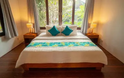 a bedroom with a bed with blue pillows and a window at Villa Jado 2 - 3 Bedroom Villa With Private Pool in Kerobokan